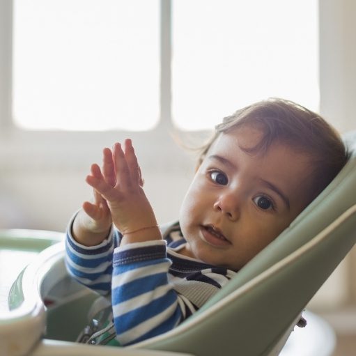 baby leaning on high chair tray