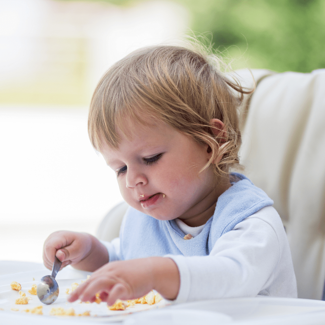 Main image for the article [My baby barely eats...is this normal?]. Pictured is a baby eating food from their highchair tray.