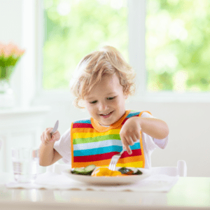 Main image for the article [The Most Likeable Veggie Dishes For Kids]. Pictured is a toddler eating a plate of vegetables.