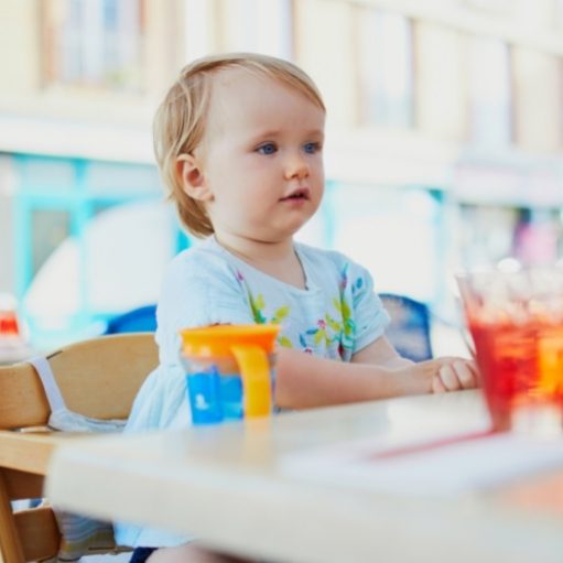 Little one sitting in a high chair with cup and straw
