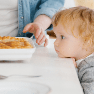 Main image for the article [The Many Forms of Pressure at Mealtimes]. Pictured is a toddler looking at a big dish of food.