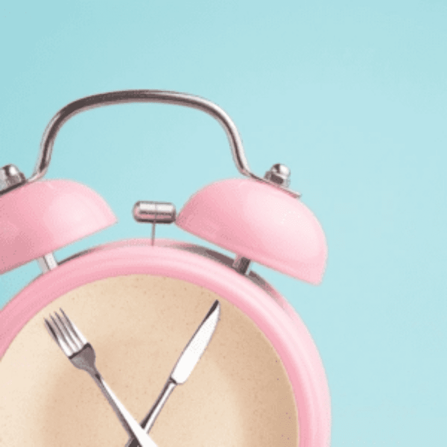 Pink alarm clock with a fork and a knife for hands.
