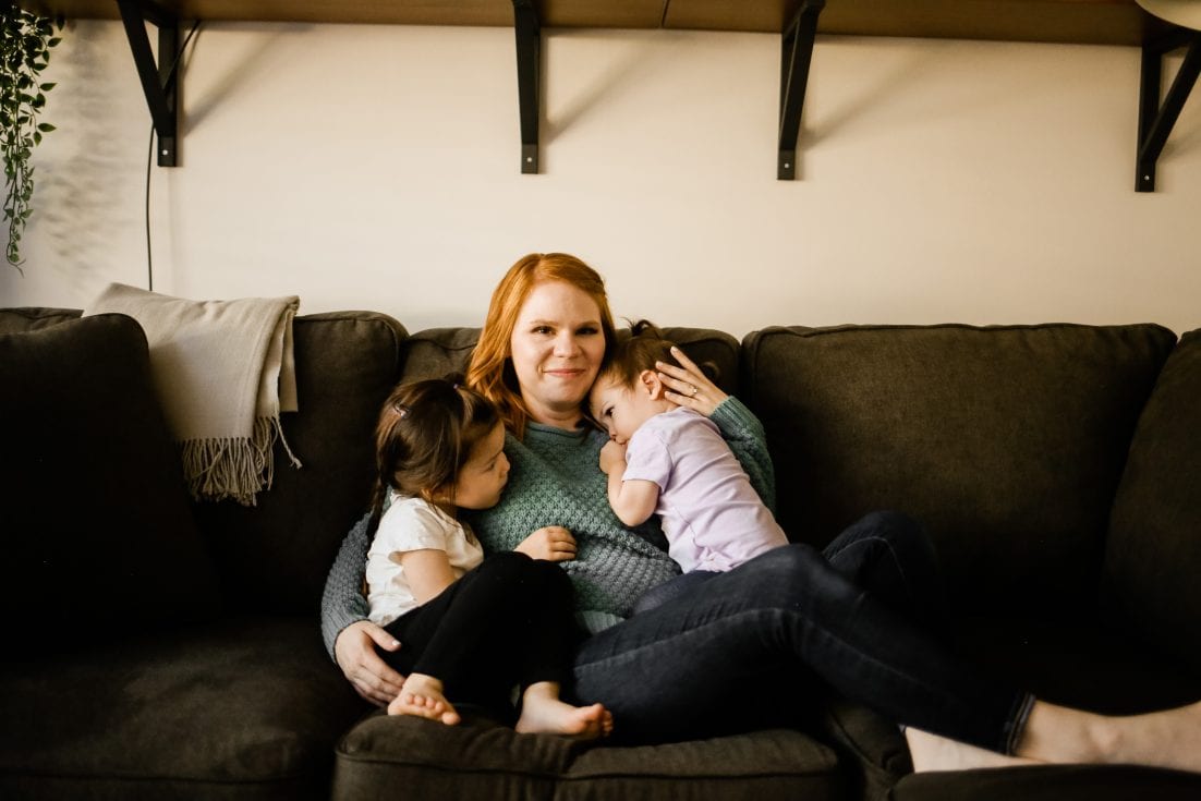 Pictured are Holly Choi and her two daughters on a dark coloured couch.