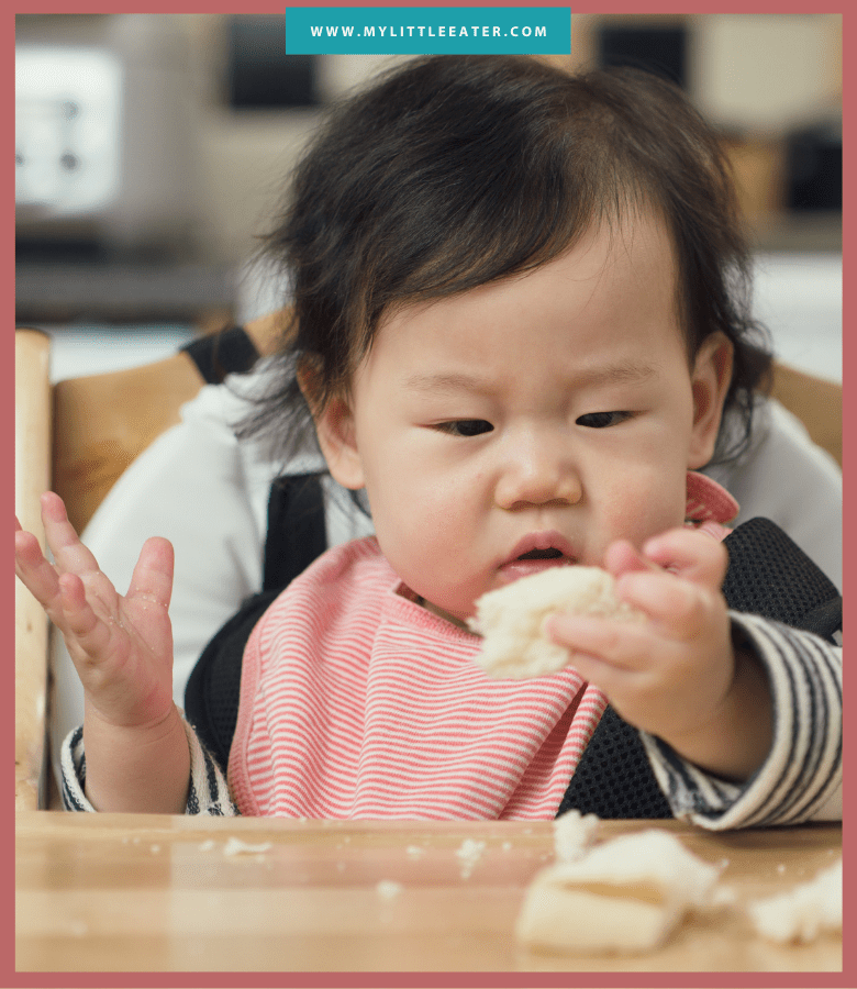 Episode art for episode "#43: The Best Bread for Baby Led Feeding." Pictured is a baby sitting in a high chair looking at a piece of bread.