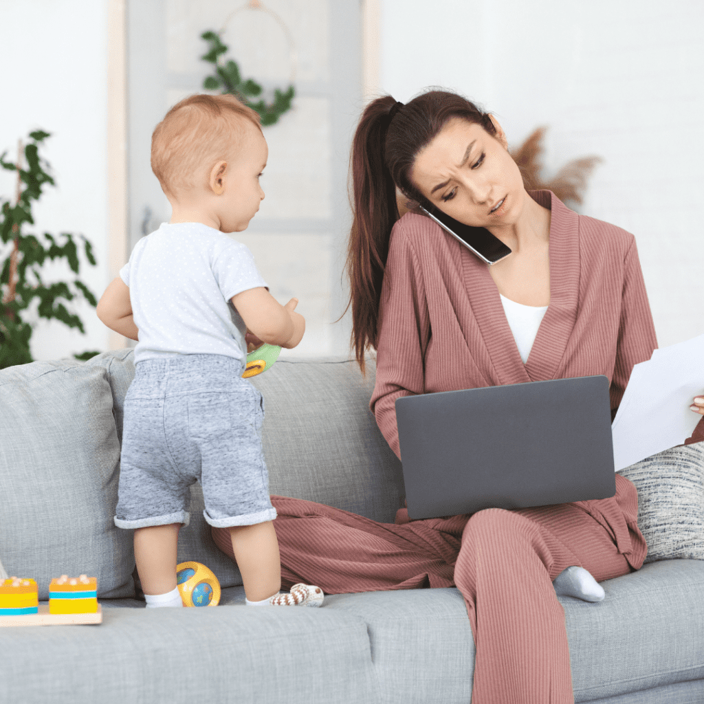 Main image for the article “The Value of a Mother’s Time and How to Make the Most of it”. Pictured is a mom sitting on the couch, doing computer work, talking on the phone, and playing with her toddler at the same time.