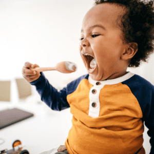 Episode art for episode: "Bonus: Toddler Led Feeding". Pictured is a toddler moving towards a spoon to take a bite.