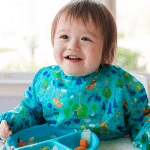 Main image for the article [What is toddler led feeding?]. Pictured is a baby sitting in a highchair, eating carrots with a fork. 