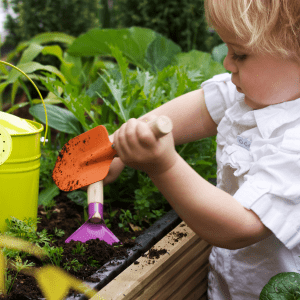 Featured image for the article: "Top Tips for Gardening with Kids". Pictured is a toddler digging in a garden.