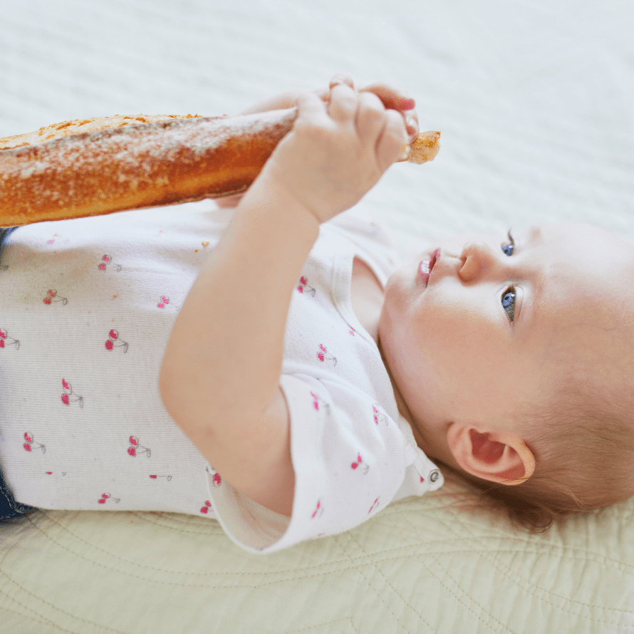 Episode art for episode: “#66: Can babies and toddlers digest starch? ”. Pictured is a baby girl holding a baguette.