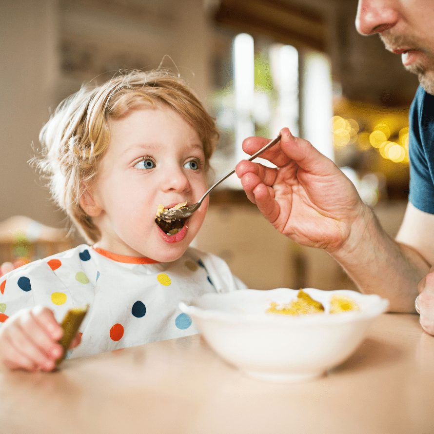 Episode art for episode: “#72: Help! My toddler won’t feed themselves!” Pictured is a toddler being fed by a parent.