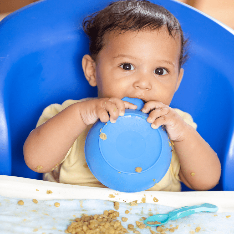 Episode art for episode: "#73: How to serve lentils to babies and toddlers ." Pictured is a baby holding a bowl close to their mouth with lentils on their tray.