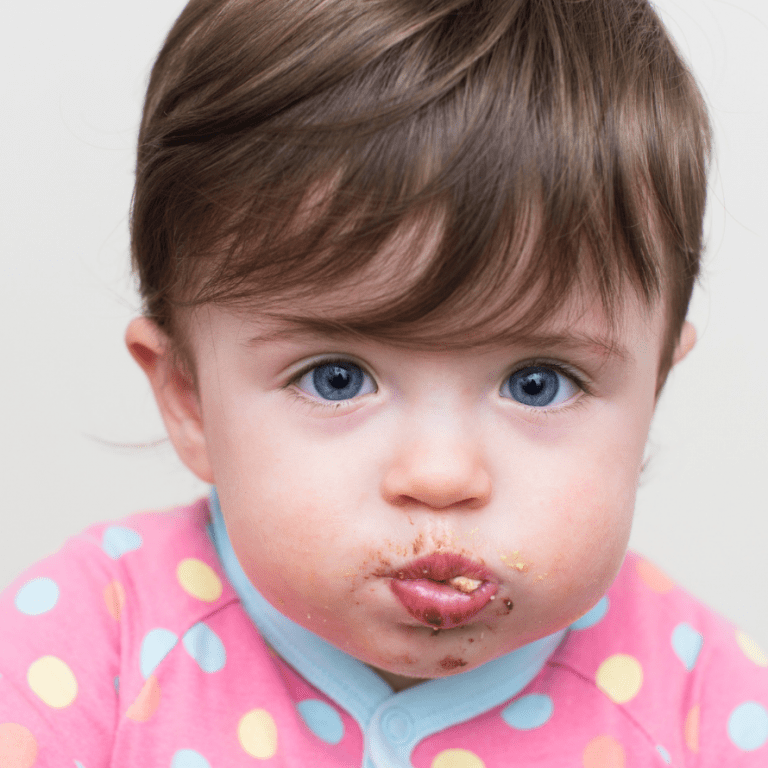 Baby with a full mouth of food after mouth stuffing.