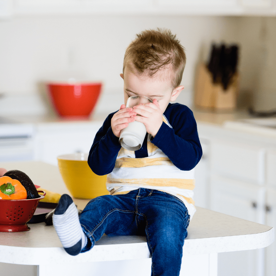 A toddler drinking a glass of milk