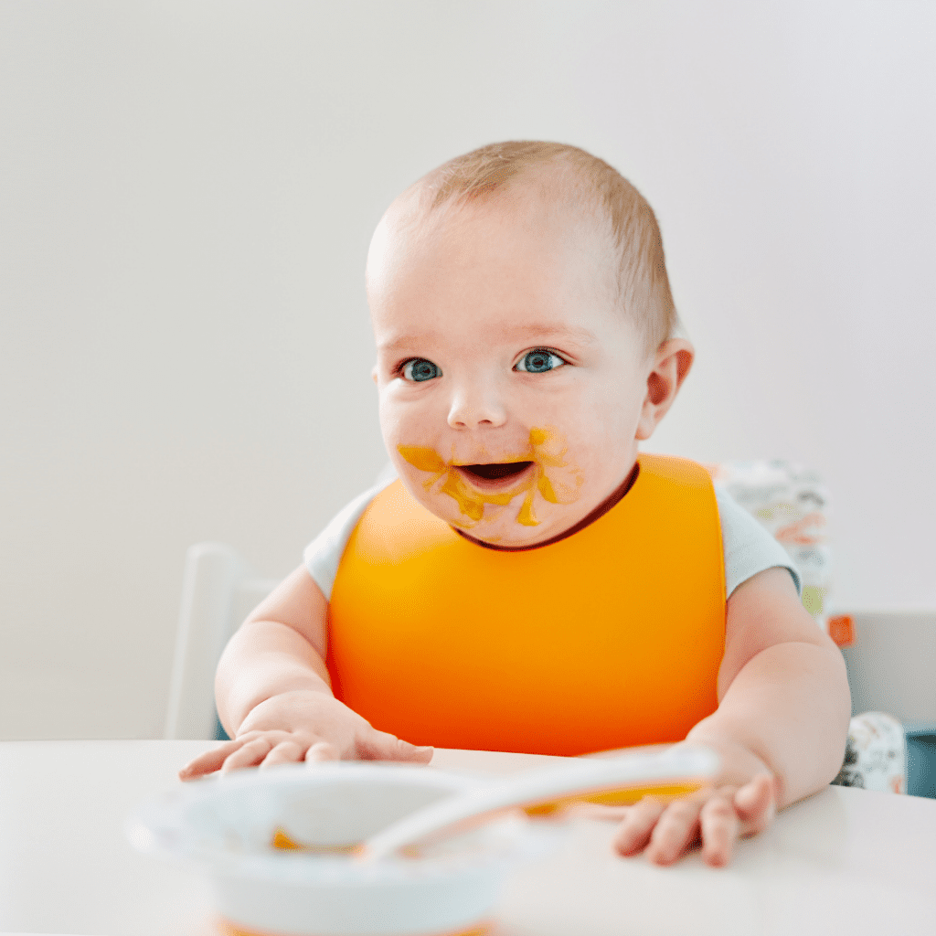 baby won't eat solids; pictured is a spoon fed baby in a high chair
