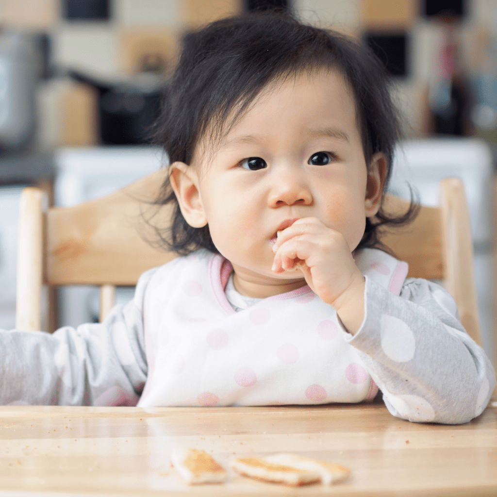 feeding baby solids too close to bed time; baby eating toast in high chair