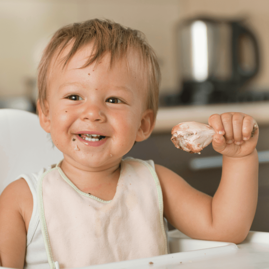 healthy fats for kids; happy toddler eating chicken drumstick