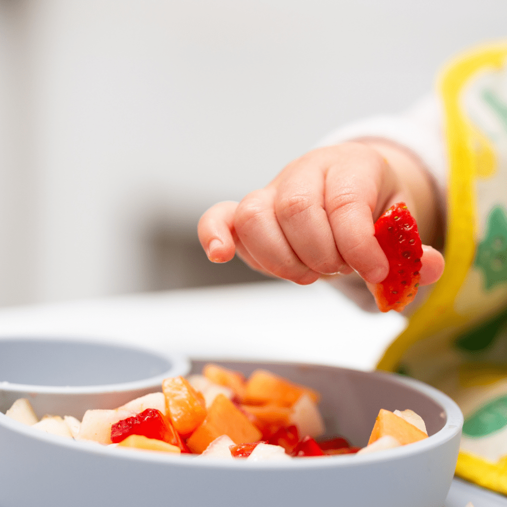Baby or toddler hungry after daycare eating some fruit.