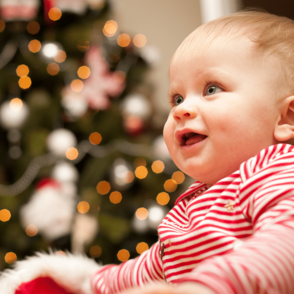Baby in front of a Christmas tree.