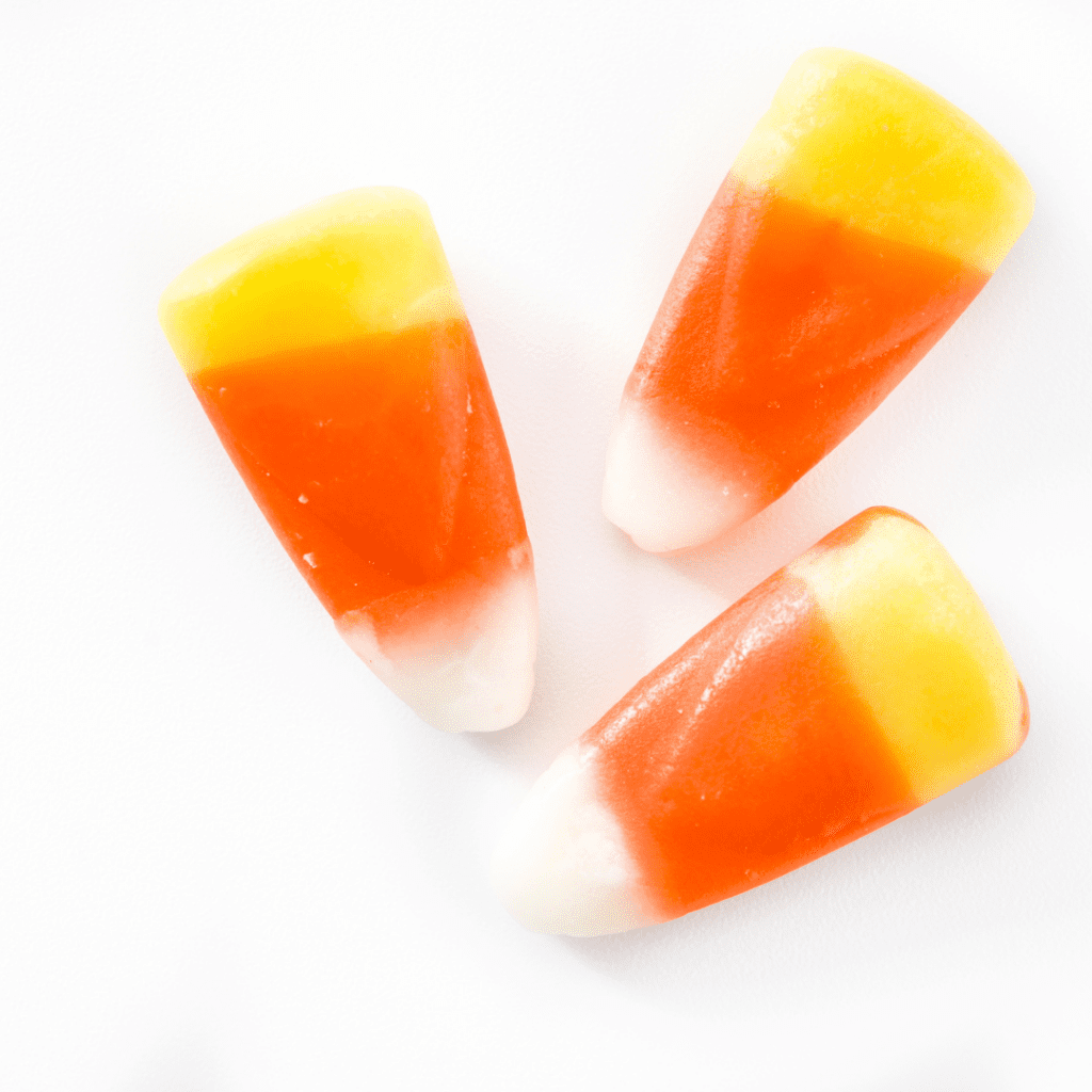 Three pieces of candy corn (a chewy candy that is orange, yellow, and white).