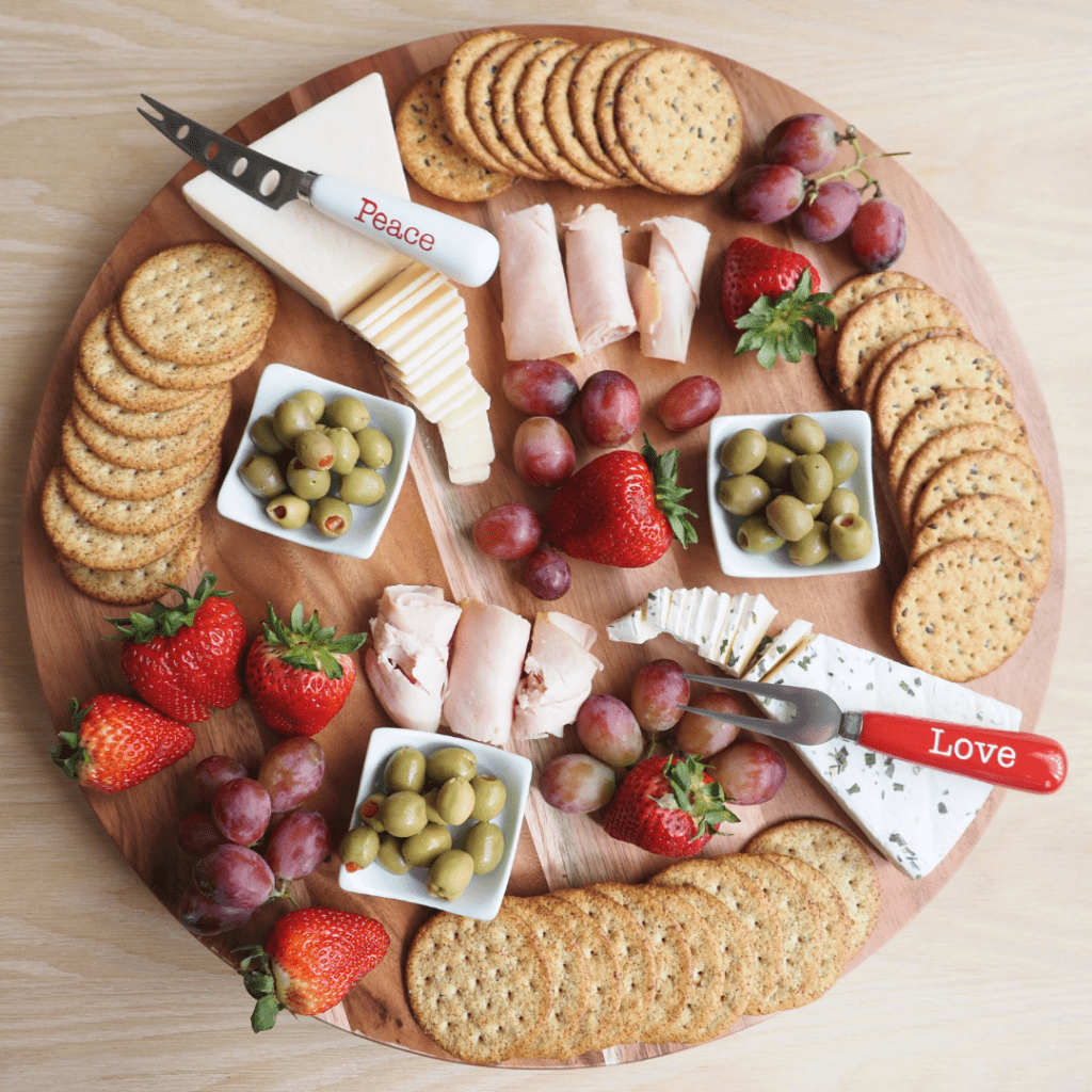 A charcuterie board with crackers, fruit, olives, cheese, and deli meat for Christmas.