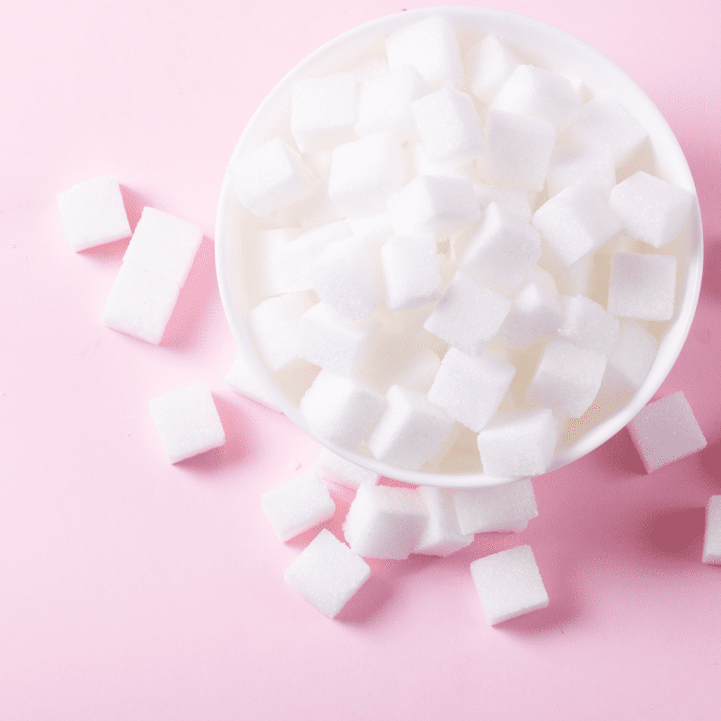 White sugar cubes in a bowl on a pink background.