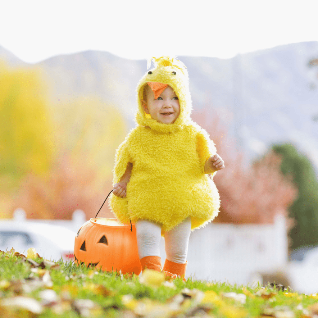 A toddler trick-or-treating as a duck.