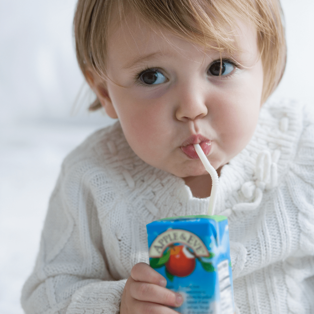 Fruit drinks and sweet drinks for toddlers; toddler drinking a juice box.