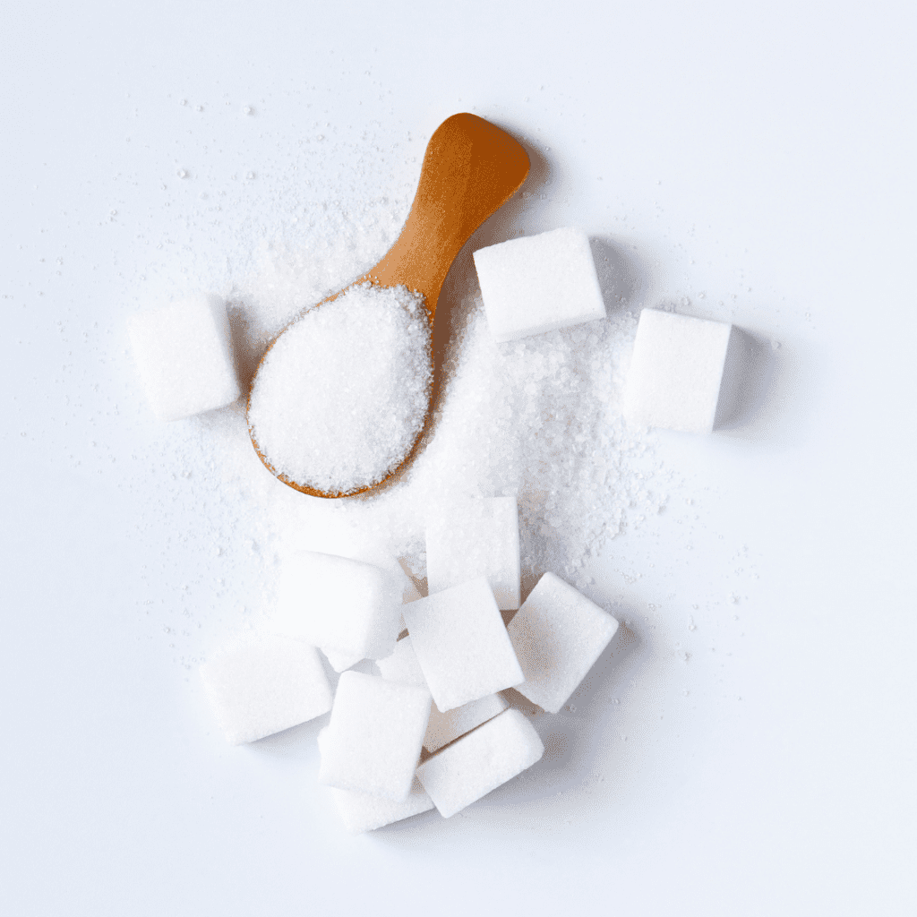 White sugar on a brown spoon and sugar cubes. 