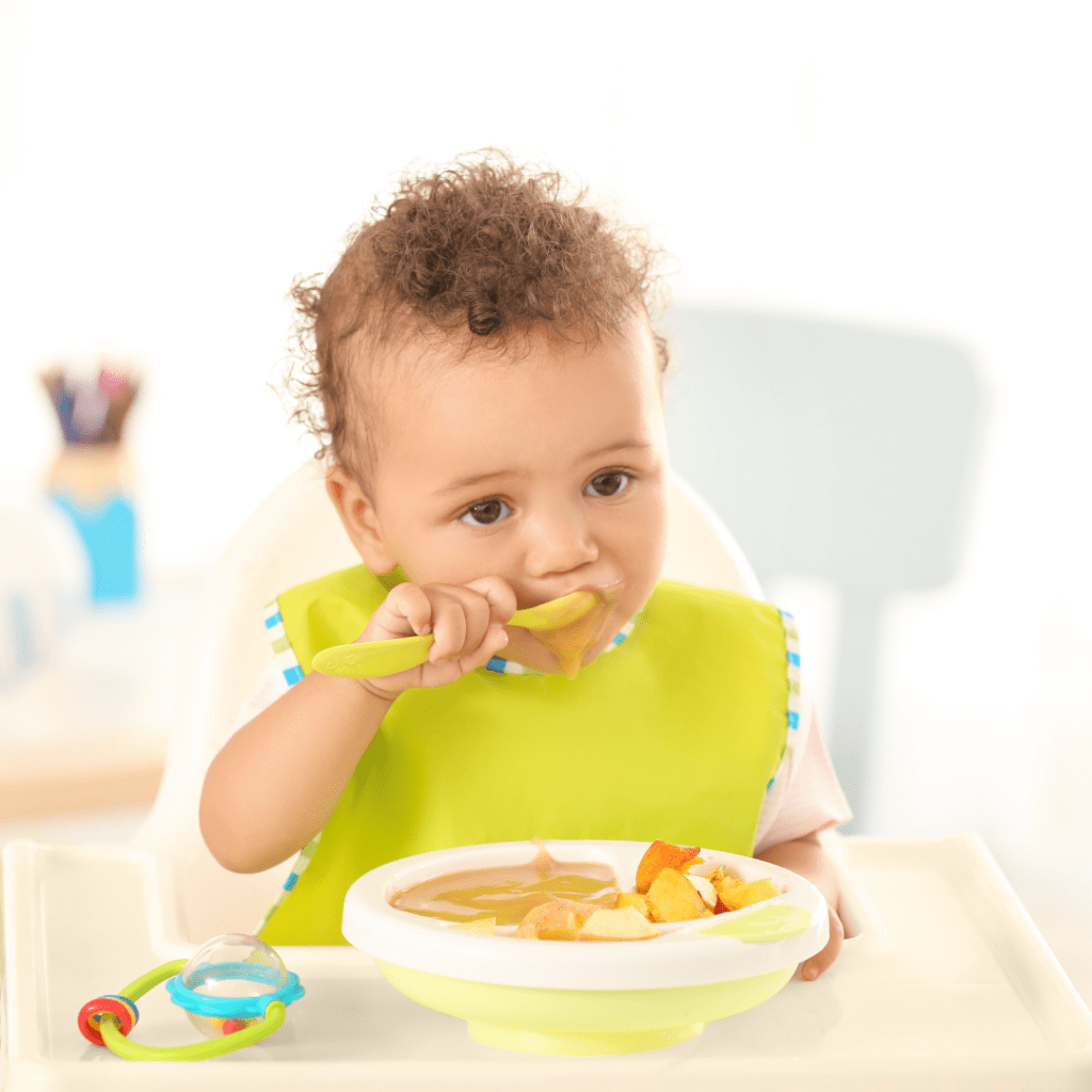 A baby eating a puree and other foods served in wedge shapes for baby led weaning.