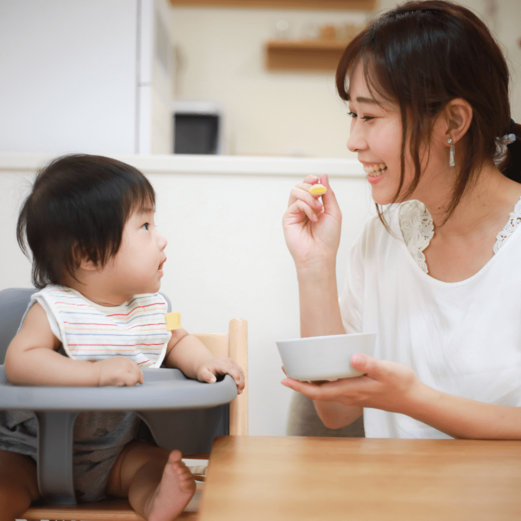 A mom serving the first foods for baby on a spoon.