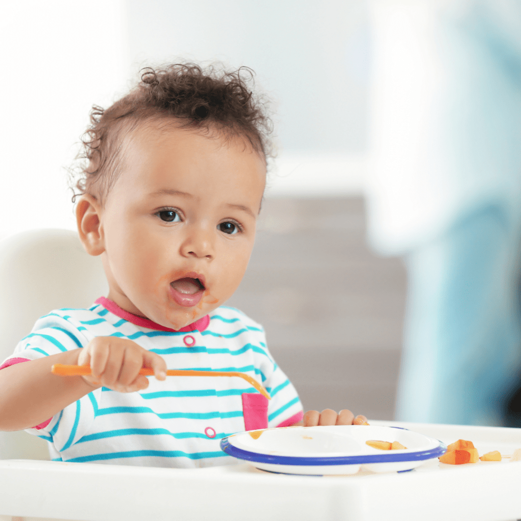 A baby eating solids at the table.