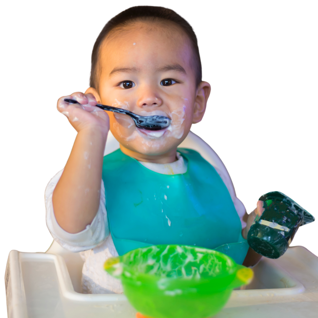Baby uses a spoon to eat a yogurt cup.