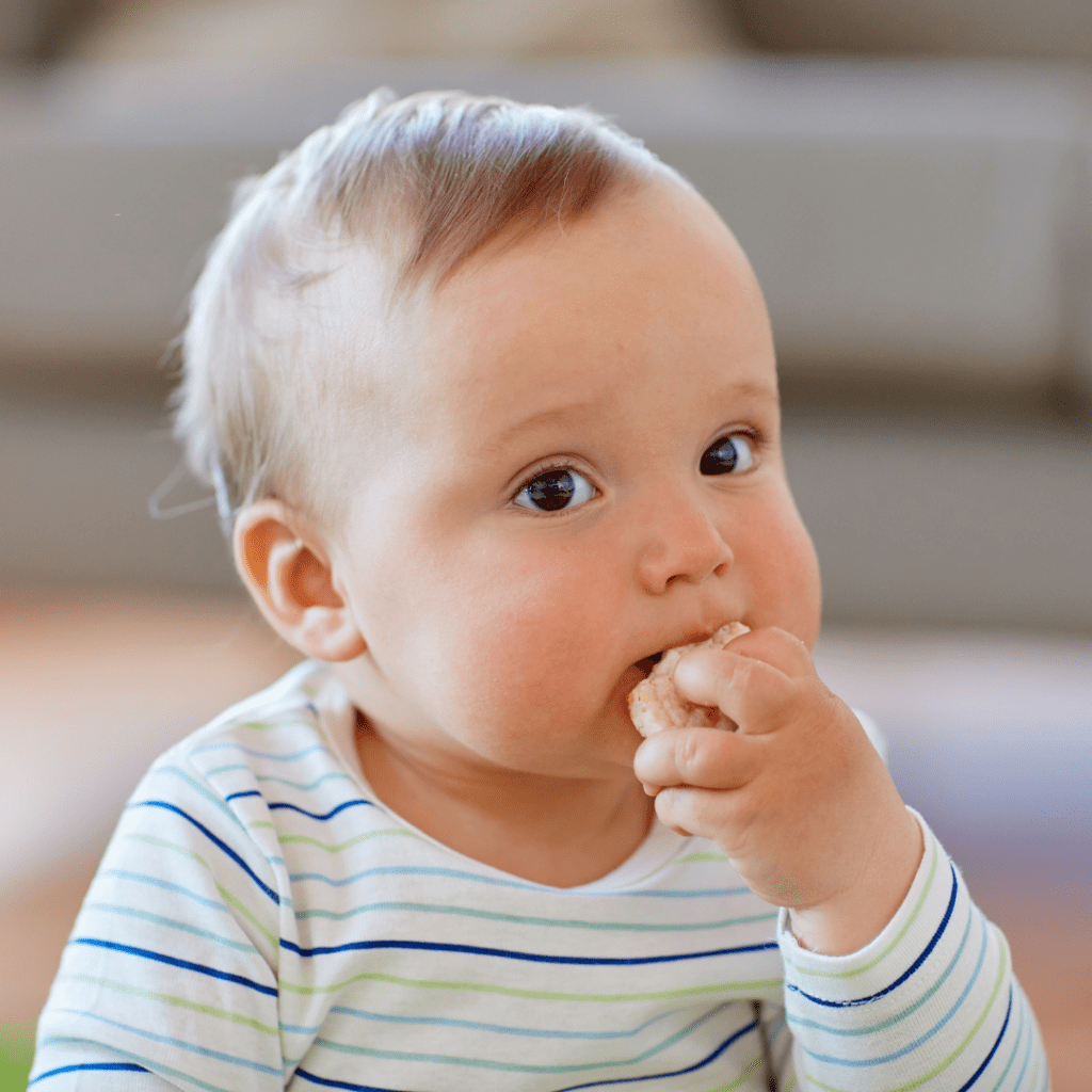 Close-up image of baby self-feeding finger food.
