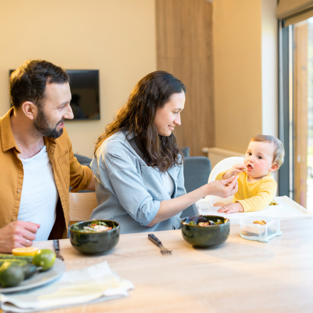 Family sitting at the dinner table have a meal with baby in high chair to reduce risk of choking.