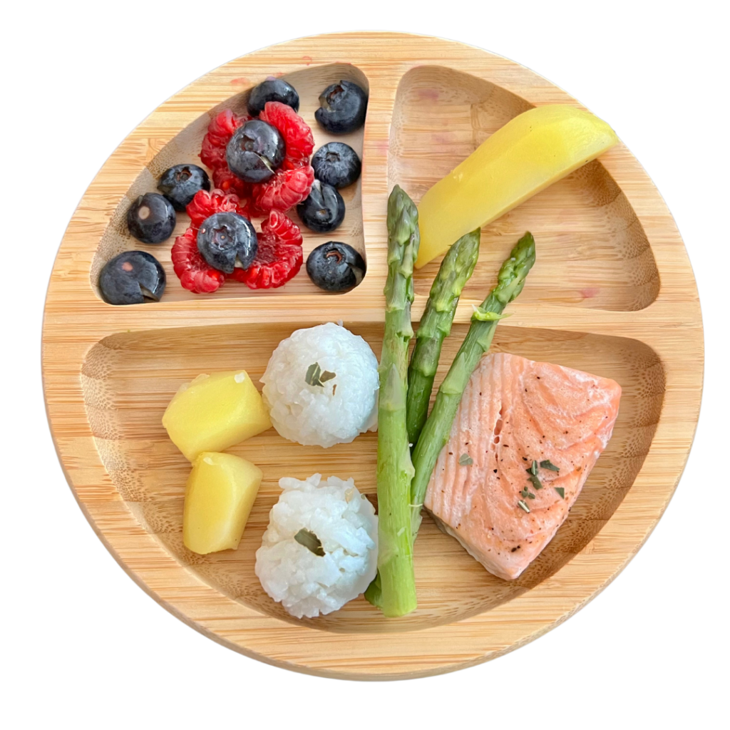 Baby led weaning meal, plated, that resembles most family meals and includes salmon, asparagus, rice, and berries.