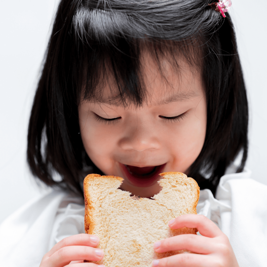 Toddler eating white bread that is not toasted.