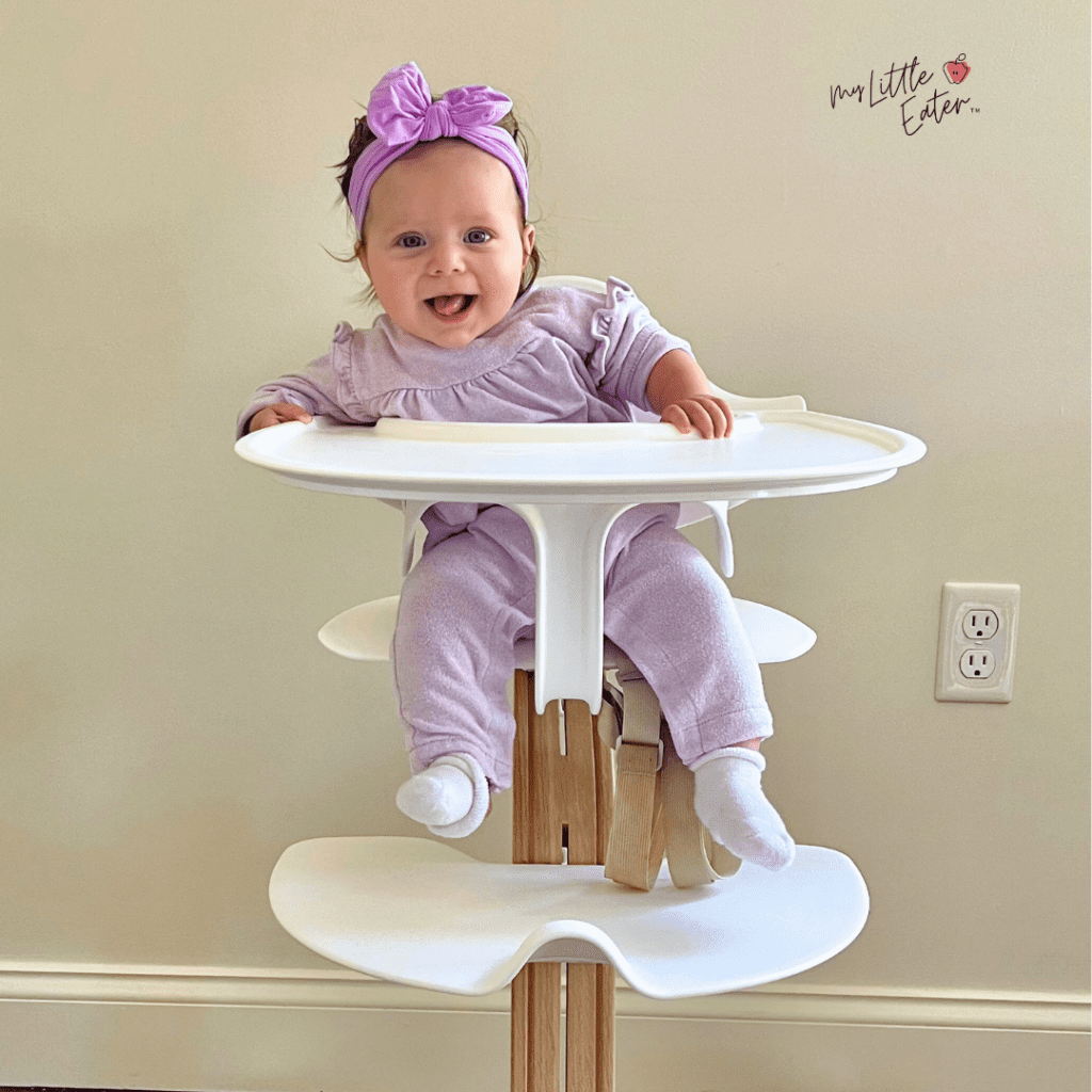 Baby at 4 months old in a high chair, leaning to the side and not showing all readiness signs for solid foods.