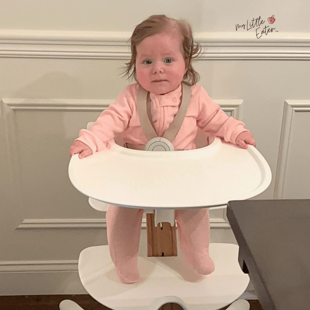 Baby at 6 months and 1 day old sitting in high chair unassisted and ready to start solid foods with baby led weaning.