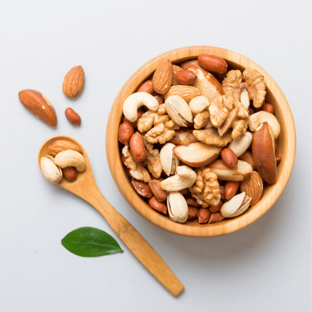 A bowl filled with various whole nuts and a spoon beside it.