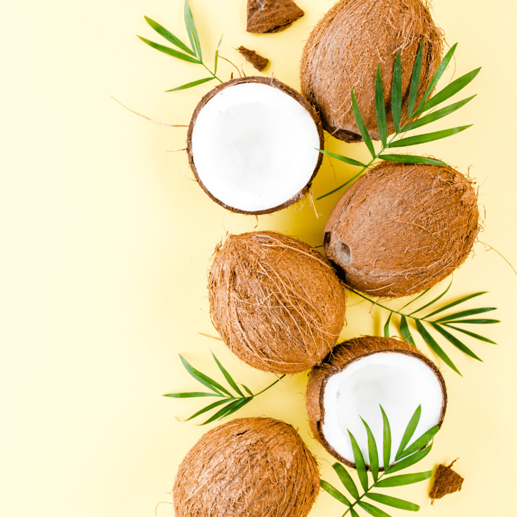 Multiple coconuts, some halved and some whole.