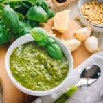 Baby pasta recipe; low-sodium pesto in a bowl surrounded by ingredients.