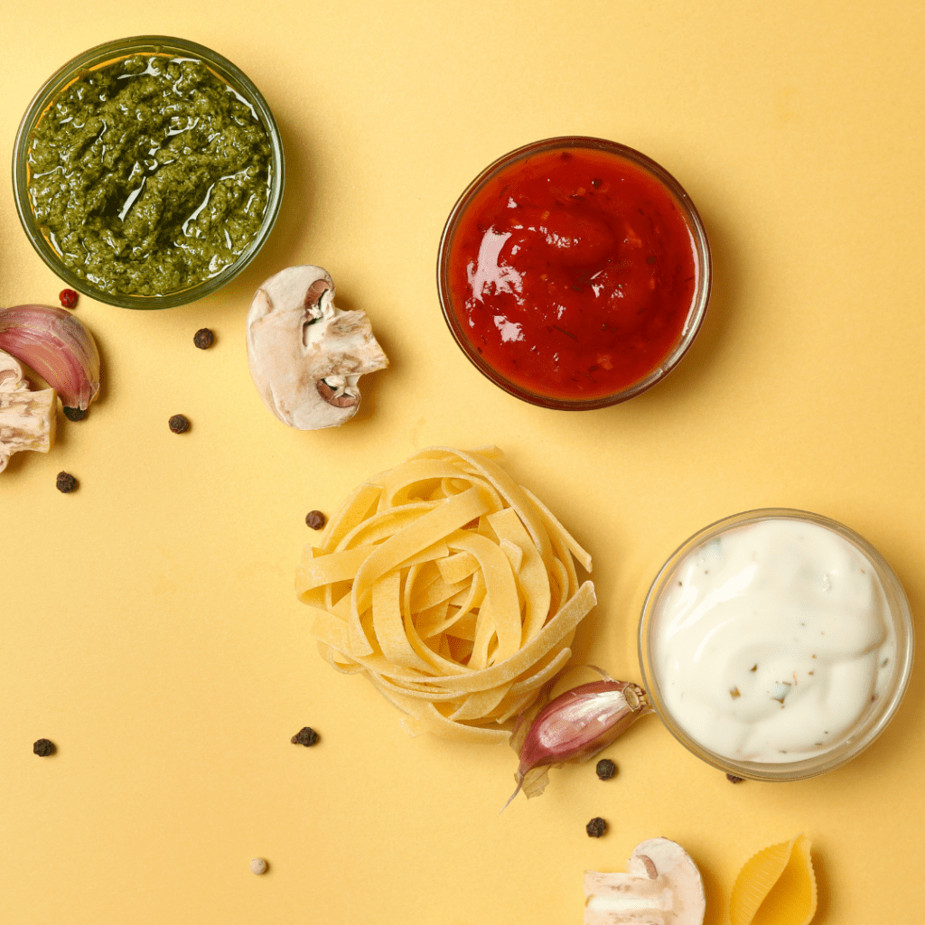 Pasta rolled into a ball, surround by 3 sauce options: pesto, spaghetti sauce, and alfredo sauce.