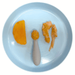 Baby plate showing cooking chicken thigh with peanut sauce served as a finger food, chicken and butternut squash mash on a preloaded spoon, and a slice of cooked butternut squash.