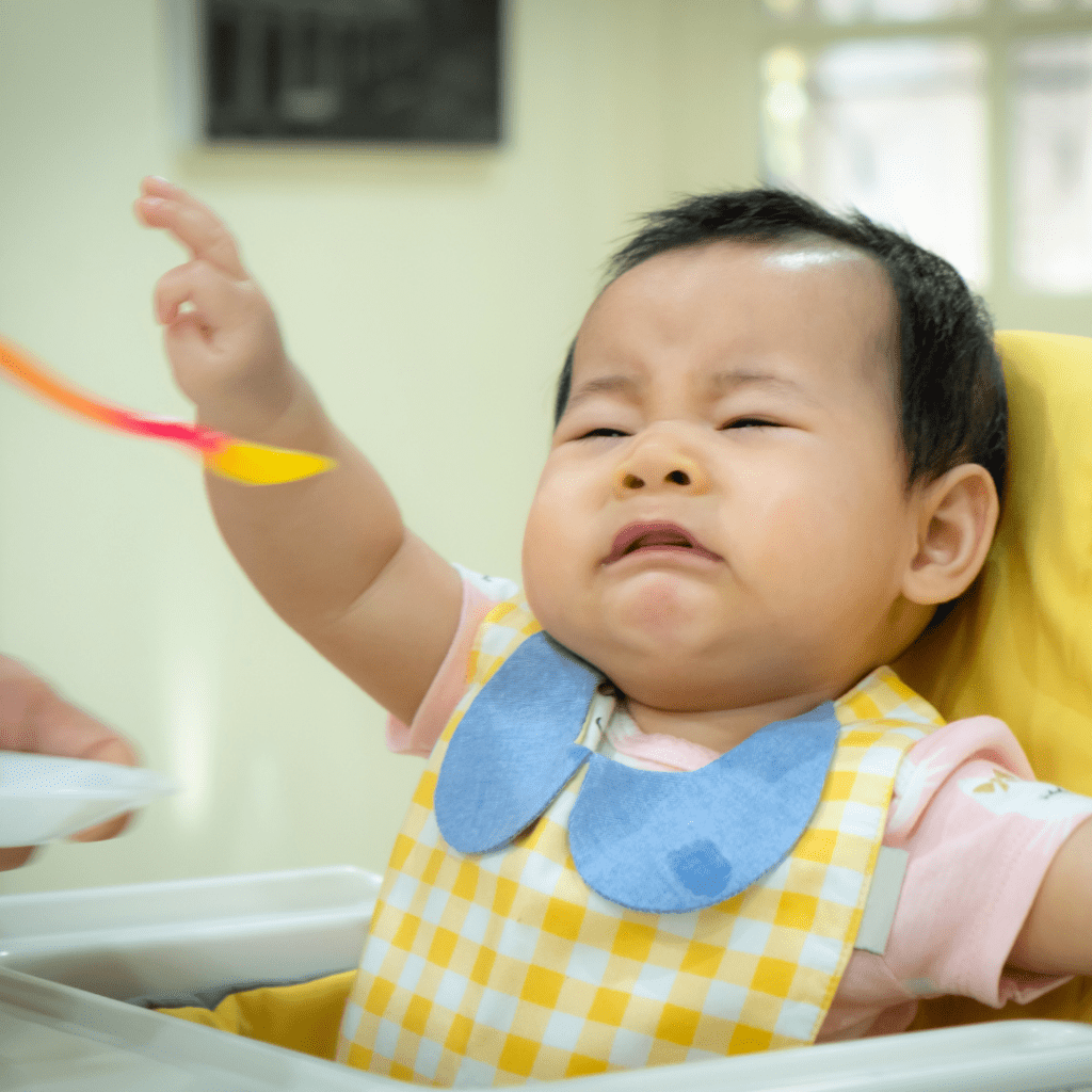 Sick children often refuse food, this baby is pushing away the spoon when parent tries to get help their child eat.