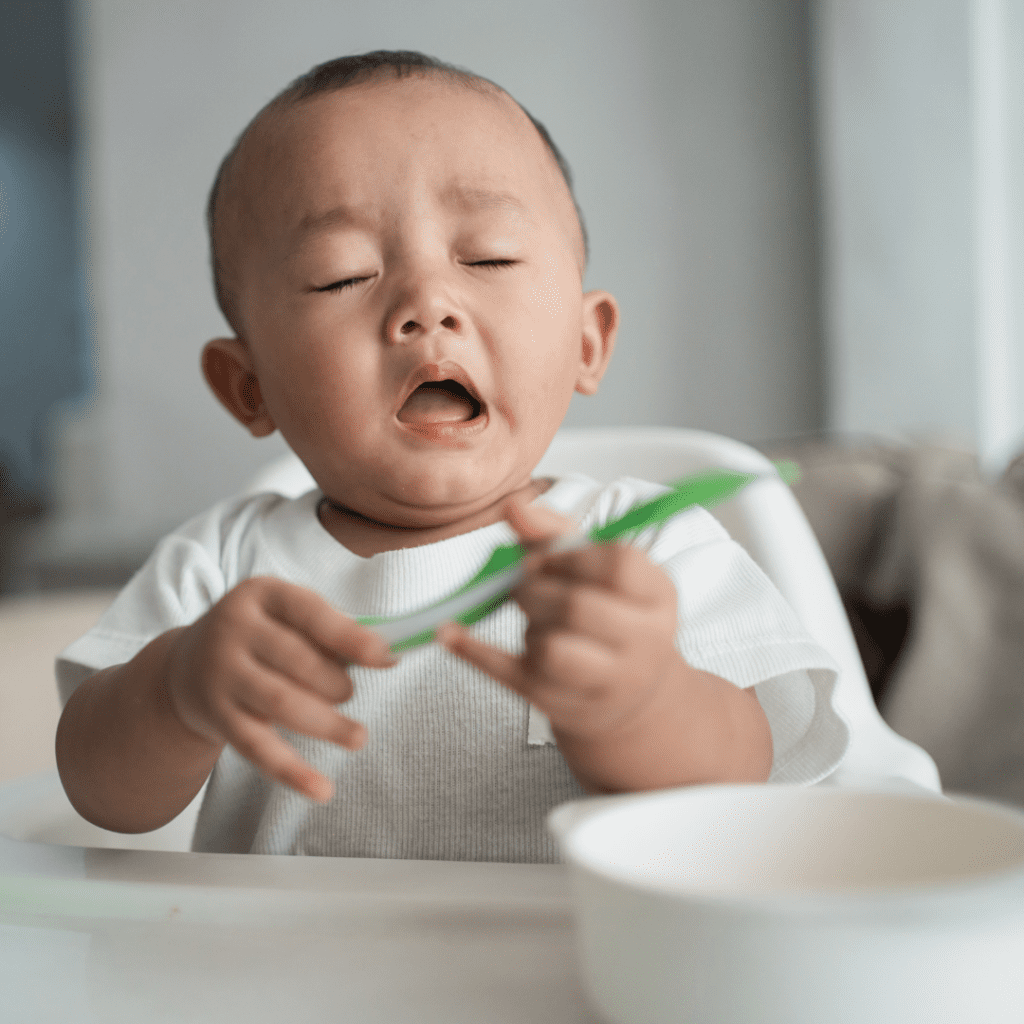 A baby in a highchair about to sneeze.