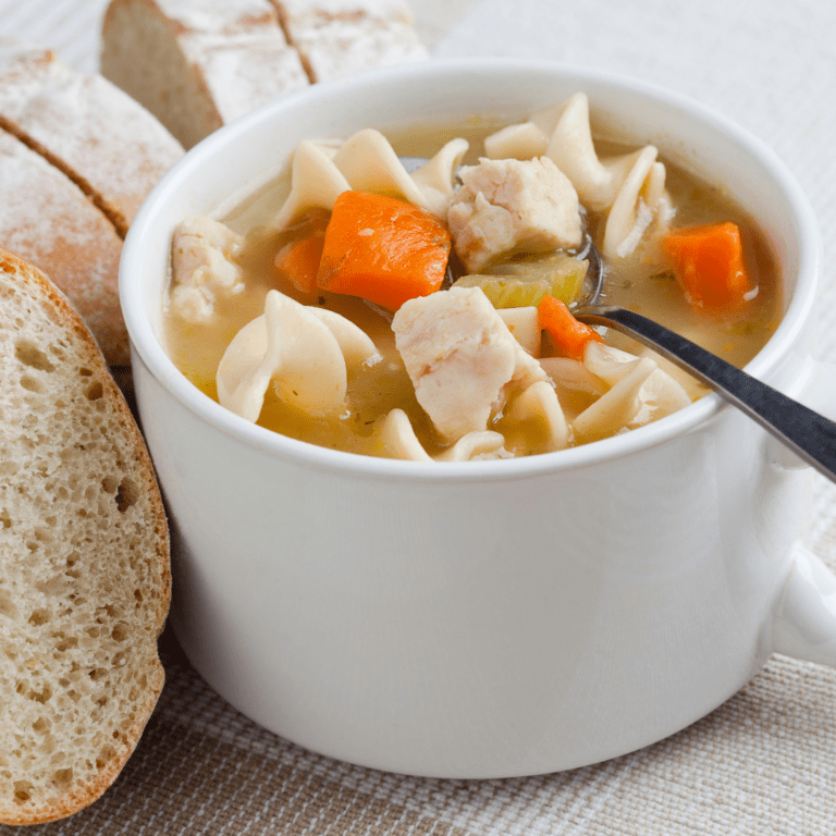 Chicken noodle soup in a cup served with bread.