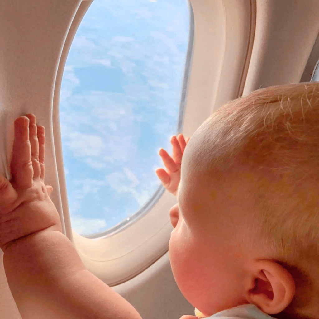 Baby looking out of the window on an airplane while flying.