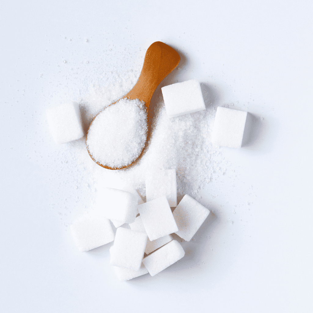 Bright image of sugar cubes and a scoop of sugar on a brown spoon.