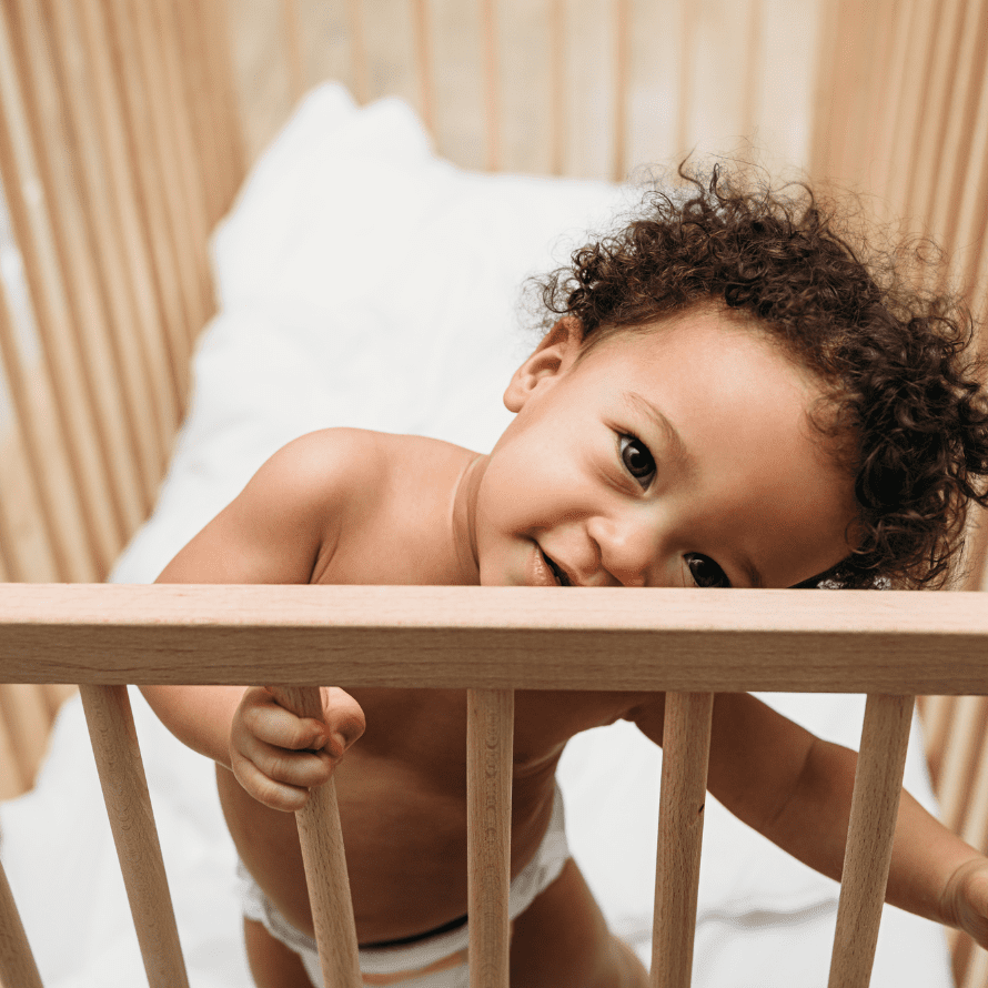A baby standing in their crib.