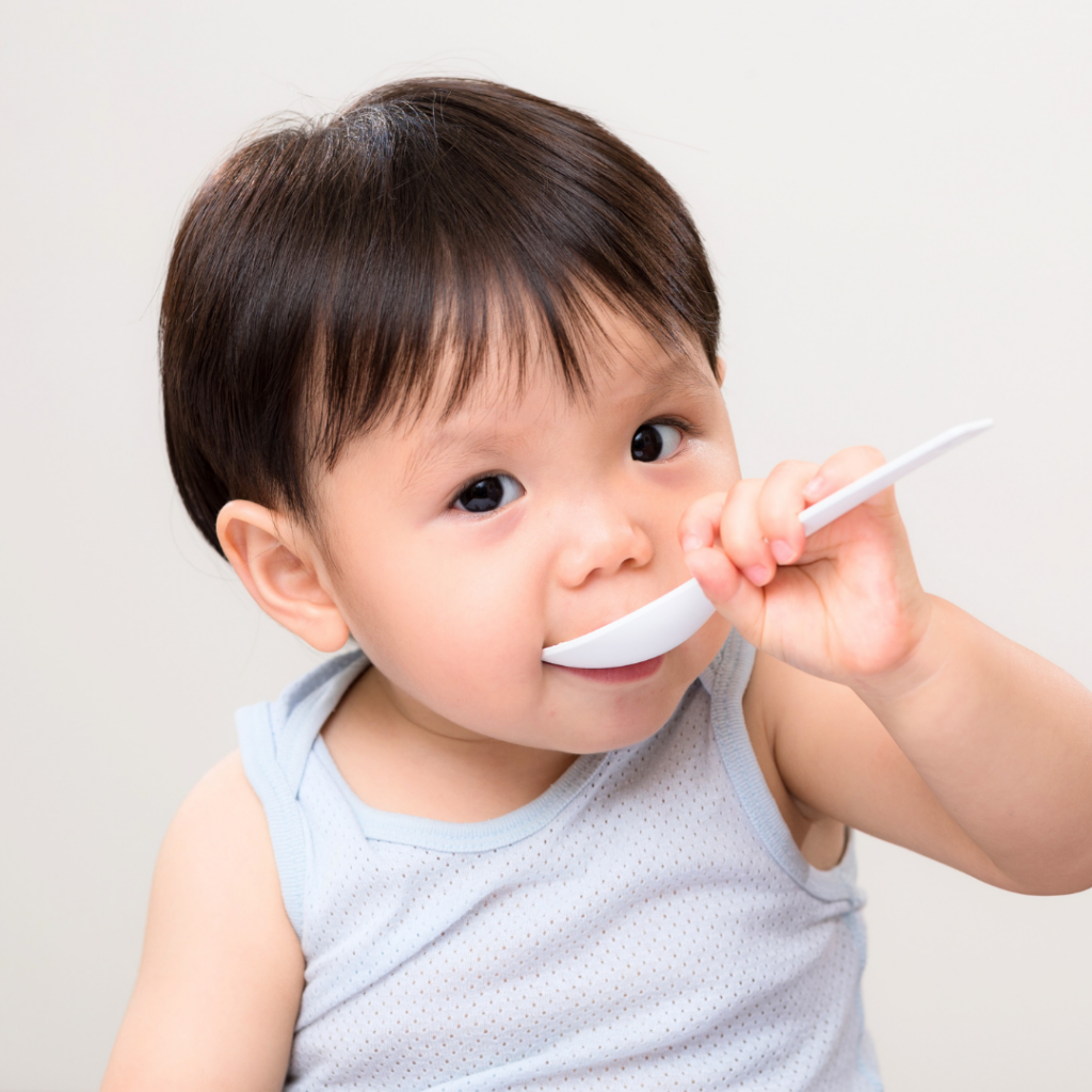 A baby eats some type of food from a spoon.